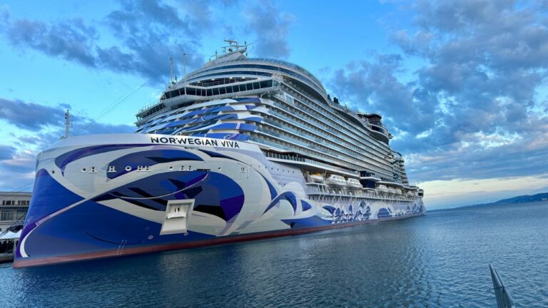 A Norwegian Viva cruise ship docked in a Southern Caribbean port under a partly cloudy sky.