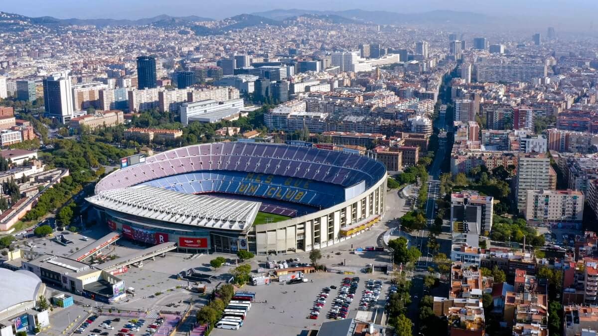 Aerial view of a large, circular stadium in Barcelona with surrounding buildings and streets on a clear day—one of the must-see things to do for cruisers exploring the city.