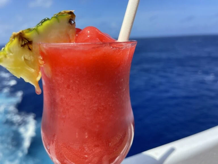 A drink with a pineapple garnish on the deck of a cruise ship.