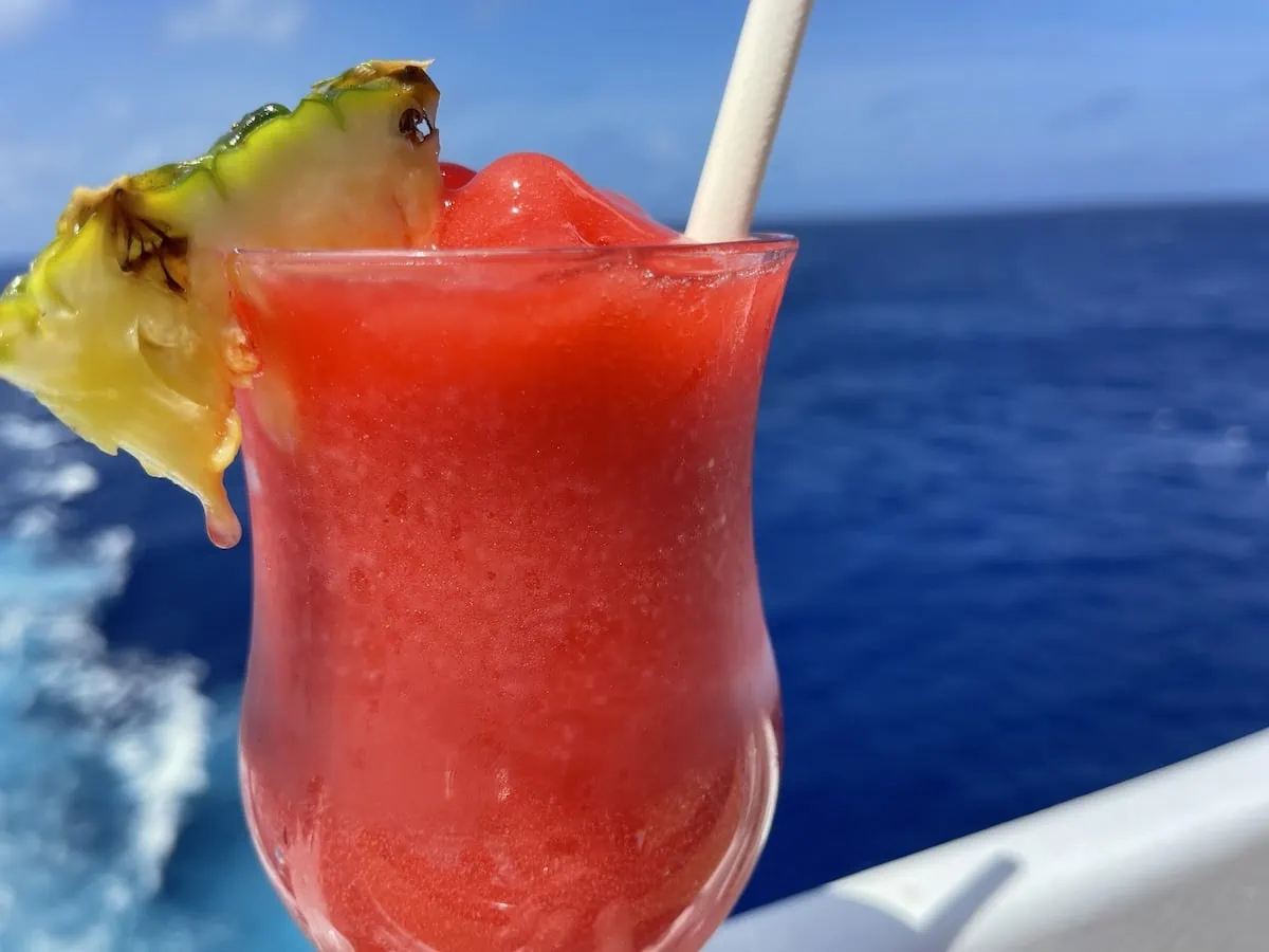 A drink with a pineapple garnish on the deck of a cruise ship.
