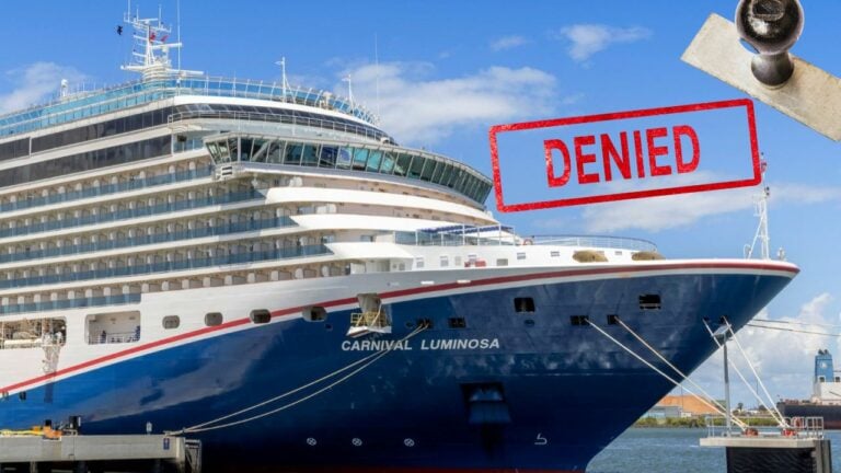 A cruise ship docked at a dock with a sign indicating denied boarding.
