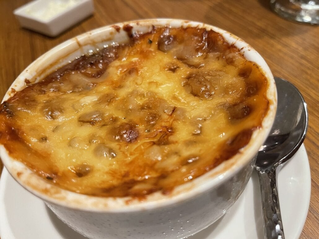 A freshly baked french onion soup with melted cheese on top in a white bowl on Carnival Mardi Gras.