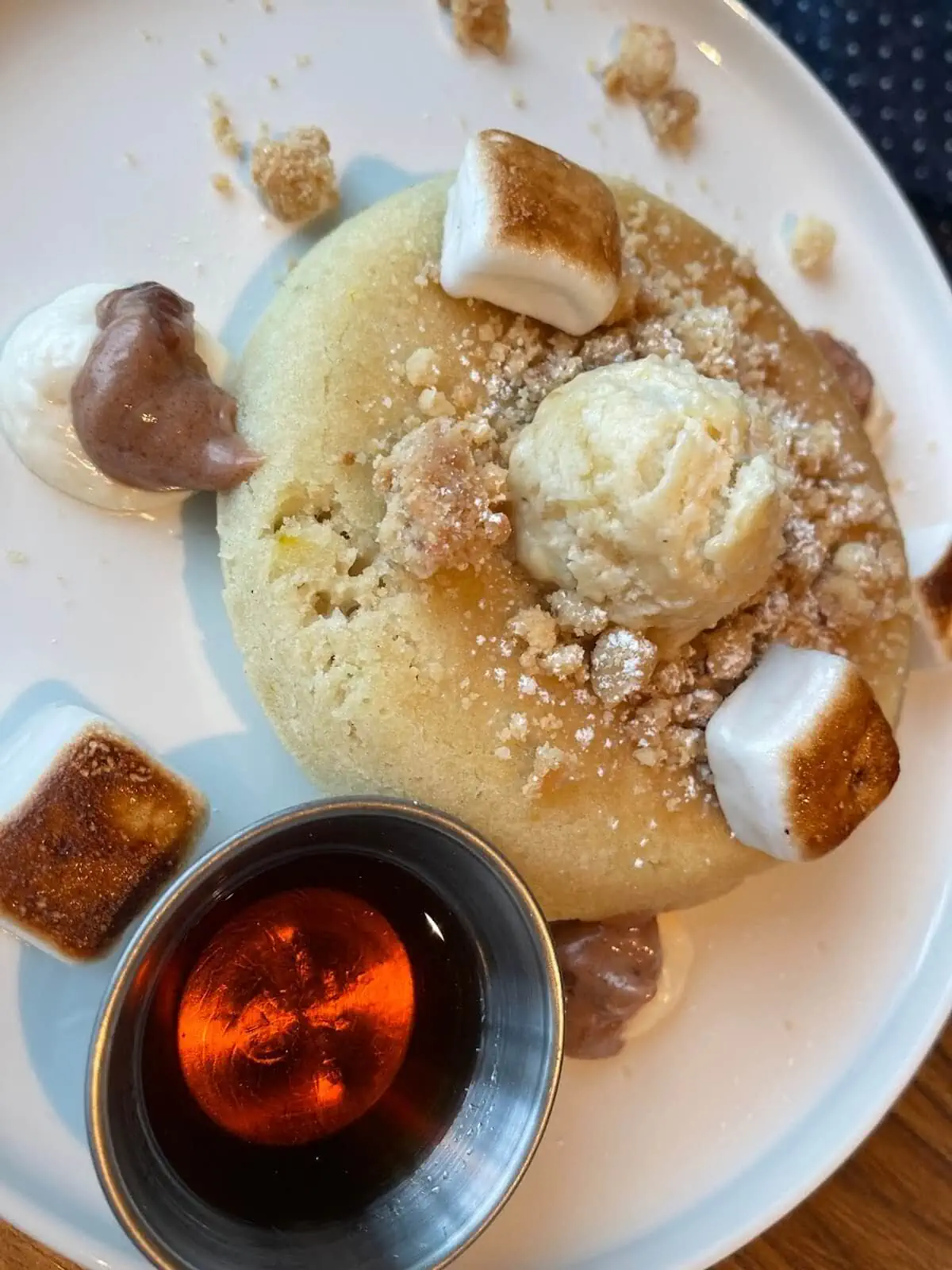 A pancake with marshmallows and syrup on a plate.