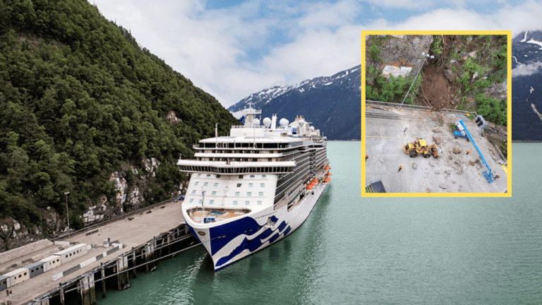 A cruise ship docked at a dock in Skagway with a mountain in the background.